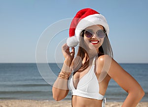 Woman wearing Santa hat and bikini on beach, space for text. Christmas vacation