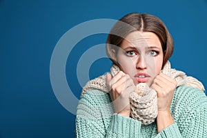 Young woman wearing scarf suffering from fever on background, space for text. Cold symptoms