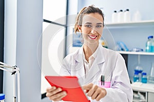 Young woman wearing scientist uniform using touchpad at laboratory