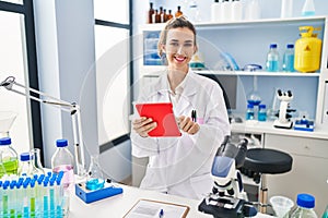 Young woman wearing scientist uniform using touchpad at laboratory