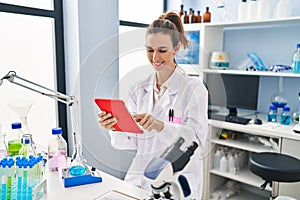 Young woman wearing scientist uniform using touchpad at laboratory