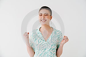 Young woman wearing shirt laughing while making winner gesture