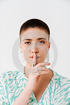 Young woman wearing shirt showing silence gesture at camera