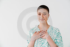 Young woman wearing shirt smiling and holding hands on her chest