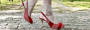 Young woman wearing slingback shoes, walking on the cobbled street by the park