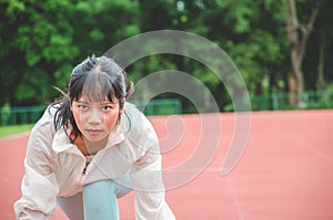 Young woman wearing sports clothes and ready to start running on the track in stadium, sport women