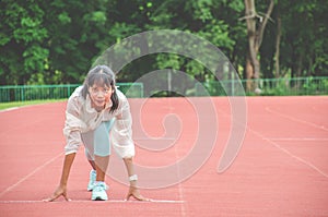 Young woman wearing sports clothes and ready to start running on the track in stadium, sport women