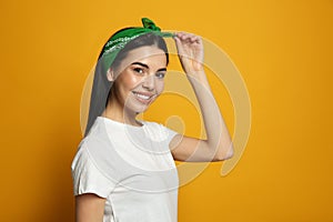 Young woman wearing stylish bandana on orange background, space for text