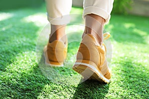 Young woman wearing stylish sneakers on grass, closeup