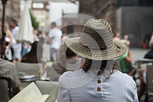 young woman wearing a summer hat sitting at the restaurant terrace
