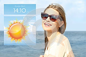 Young woman wearing sunglasses near river and weather forecast widget. Mobile application