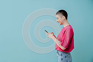 Young woman wearing t-shirt smiling and using cellphone