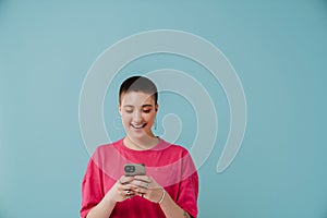 Young woman wearing t-shirt smiling and using cellphone