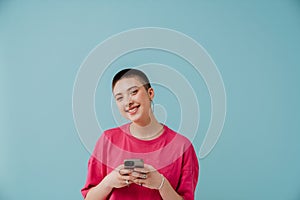 Young woman wearing t-shirt smiling and using cellphone