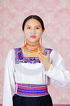 Young woman wearing traditional andean dress, facing camera doing sign language word for identification papers