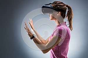 Young woman wearing virtual reality headset in studio. Emotions. Side view