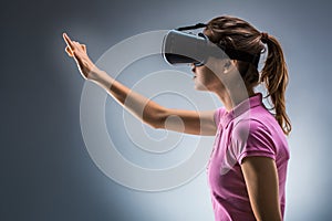 Young woman wearing virtual reality headset in studio. Emotions. Side view
