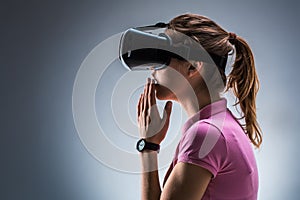 Young woman wearing virtual reality headset in studio. Emotions. Side view