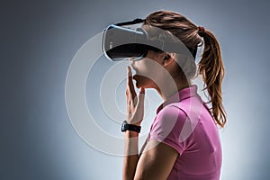 Young woman wearing virtual reality headset in studio. Emotions. Side view
