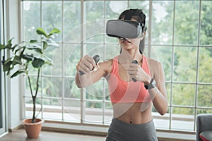 Young woman wearing VR headset doing working out interacting with 3d simulation at home