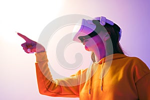 Young woman wearing a VR headset interacts with a virtual environment, symbolizing the future of gaming, metaverse, digital