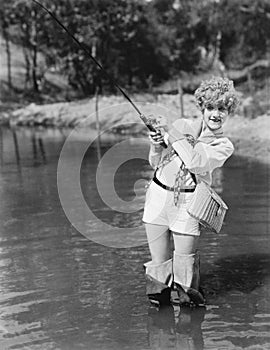 Young woman wearing waders holding a fishing rod photo