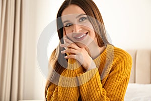 Young woman wearing warm sweater on bed. Winter season