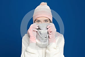 Young woman wearing warm sweater, gloves, scarf and hat on background. Winter season