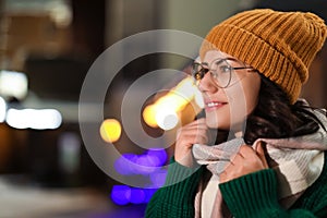 Young woman wearing warm sweater, hat and scarf  at night. Winter season