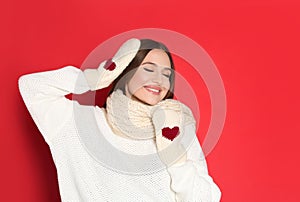 Young woman wearing warm sweater and mittens on background. Winter season