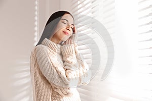 Young woman wearing warm sweater near window. Winter season