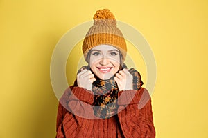 Young woman wearing warm sweater, scarf and hat on background. Winter season