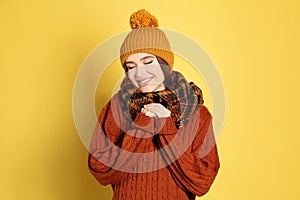 Young woman wearing warm sweater, scarf and hat on background. Winter season
