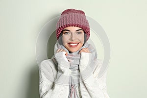 Young woman wearing warm sweater, scarf and hat on background. Winter season
