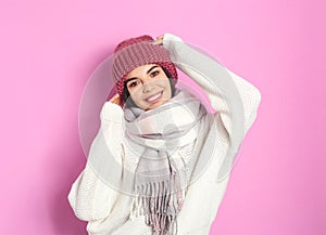 Young woman wearing warm sweater, scarf and hat on background. Winter season