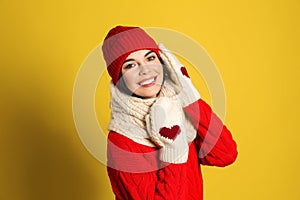 Young woman wearing warm sweater, scarf, mittens and hat on background. Winter season