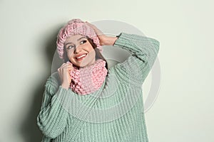 Young woman wearing warm sweater, snood and hat on background. Winter season