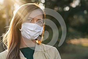 Young woman wearing white cotton virus mouth nose mask, nice bokeh in background, closeup face portrait