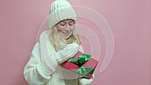 Young woman wearing white knitted sweater, scarf and hat with present box