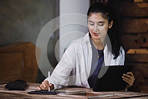 Young woman wearing white suit working using tablet at table company. creative female using online chatting on tablet at workplace