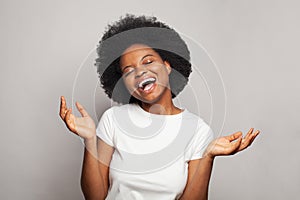 Young woman wearing white t-shirt standing over isolated grey background smiling cheerful with open arms as friendly