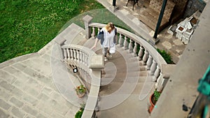 young woman wearing white t-shirt walking up the old castle stairs