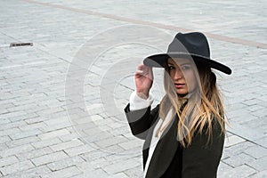 young woman wearing a winter green coat and hat in the street