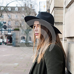 Young woman wearing a winter green coat and hat in the street