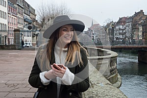 Young woman wearing a winter green coat, leather boots and hat in the street