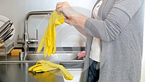 Young woman wearing yellow latex gloves before cleaning kitchen