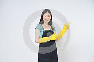 Young woman wearing yellow rubber gloves for hands protection and pointing to empty copy space isolated on white background