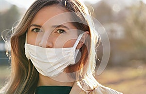 Young woman wears home made white cotton mouth face mask, wrong way, incorrect wearing - masks should cover nose as well