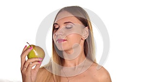 Young woman wears red lipstick and has her hair down, and brushed, eating a big, dark red apple and juicy pear