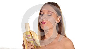 Young woman wears red lipstick and has her hair down, and brushed, peeling and eating a big banana. healthy food -